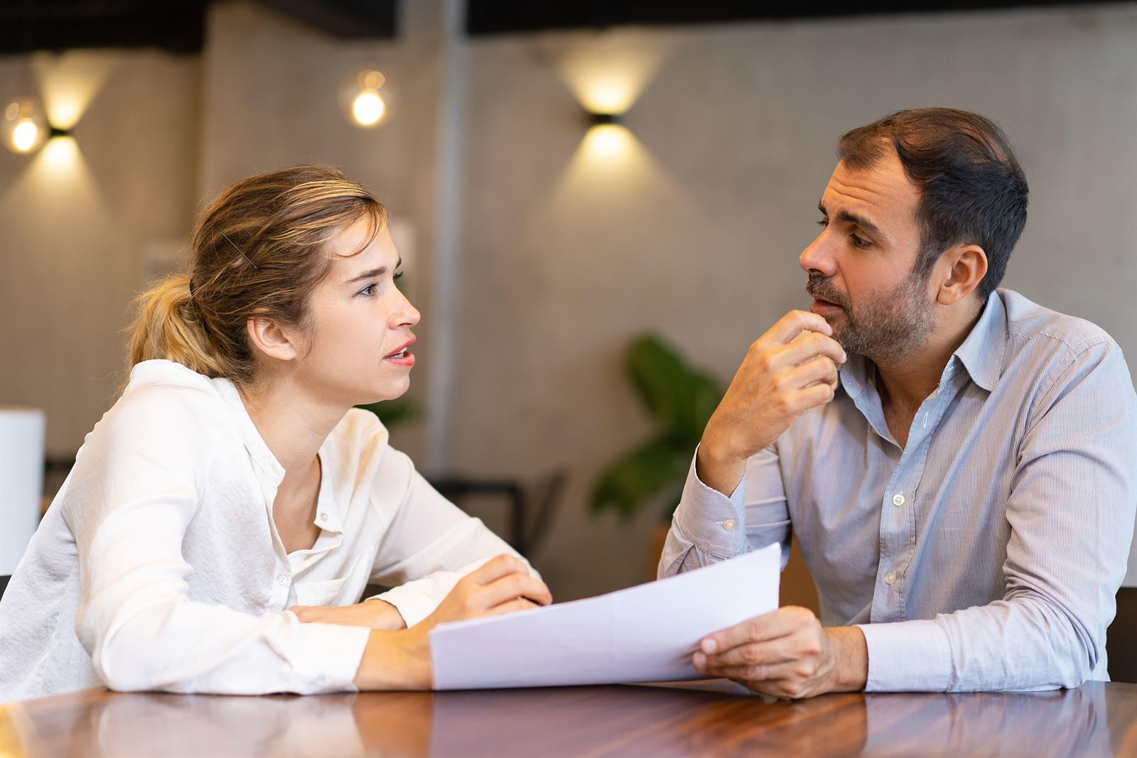 Una mujer y un hombre revisan juntos un documento en una mesa de trabajo